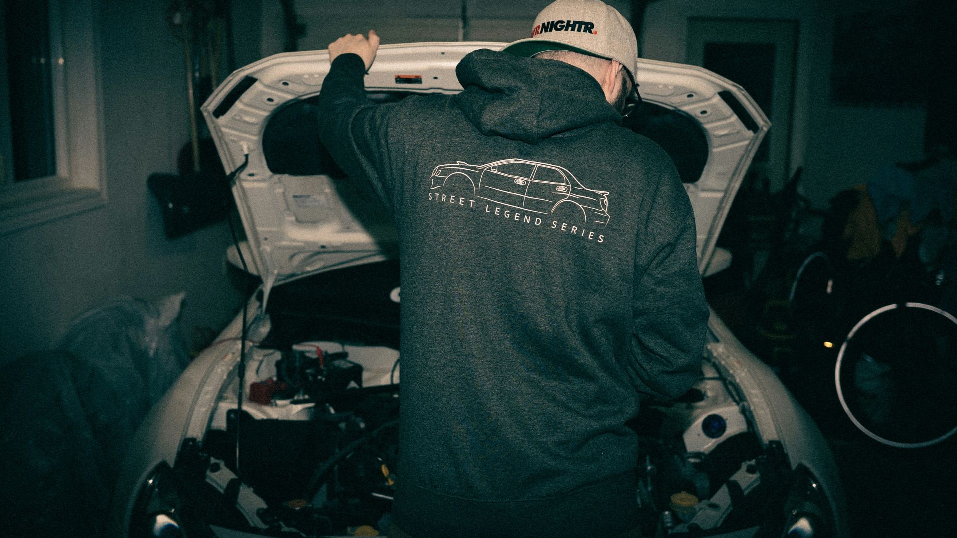 a man standing next to a car in a garage