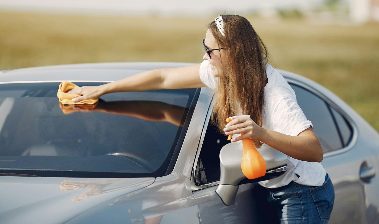 Young woman wiping automobile