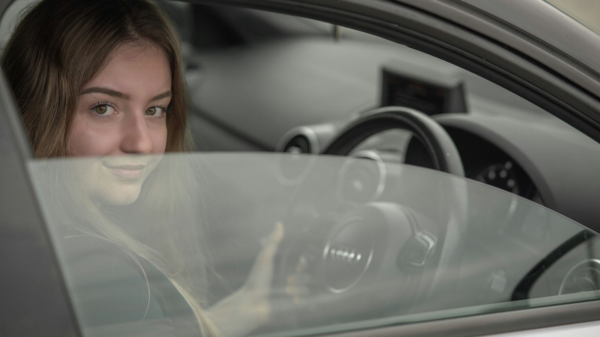 a woman sitting in a car holding a steering wheel