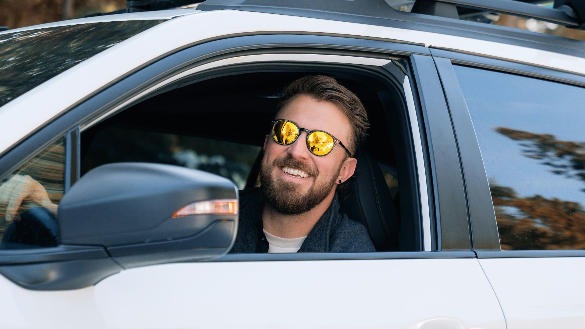 a man wearing sunglasses sitting in a white car