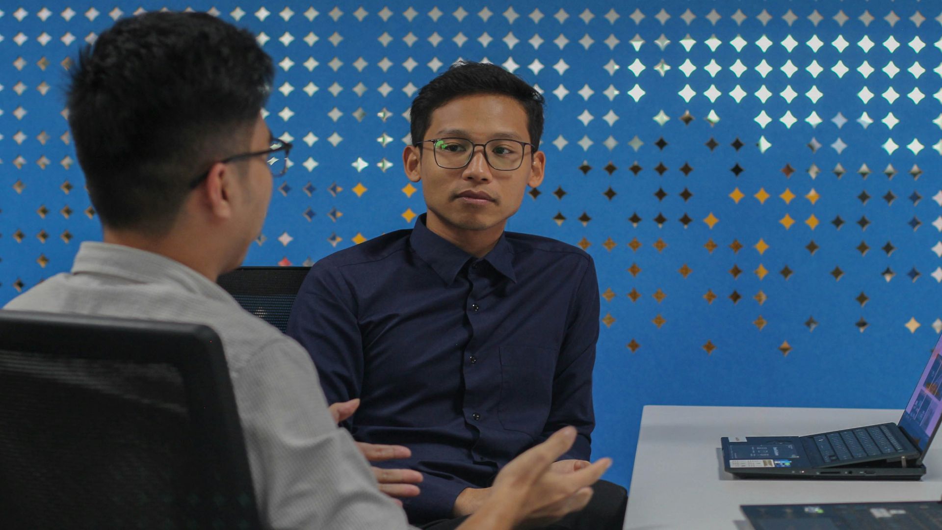 two men sitting at a table talking to each other