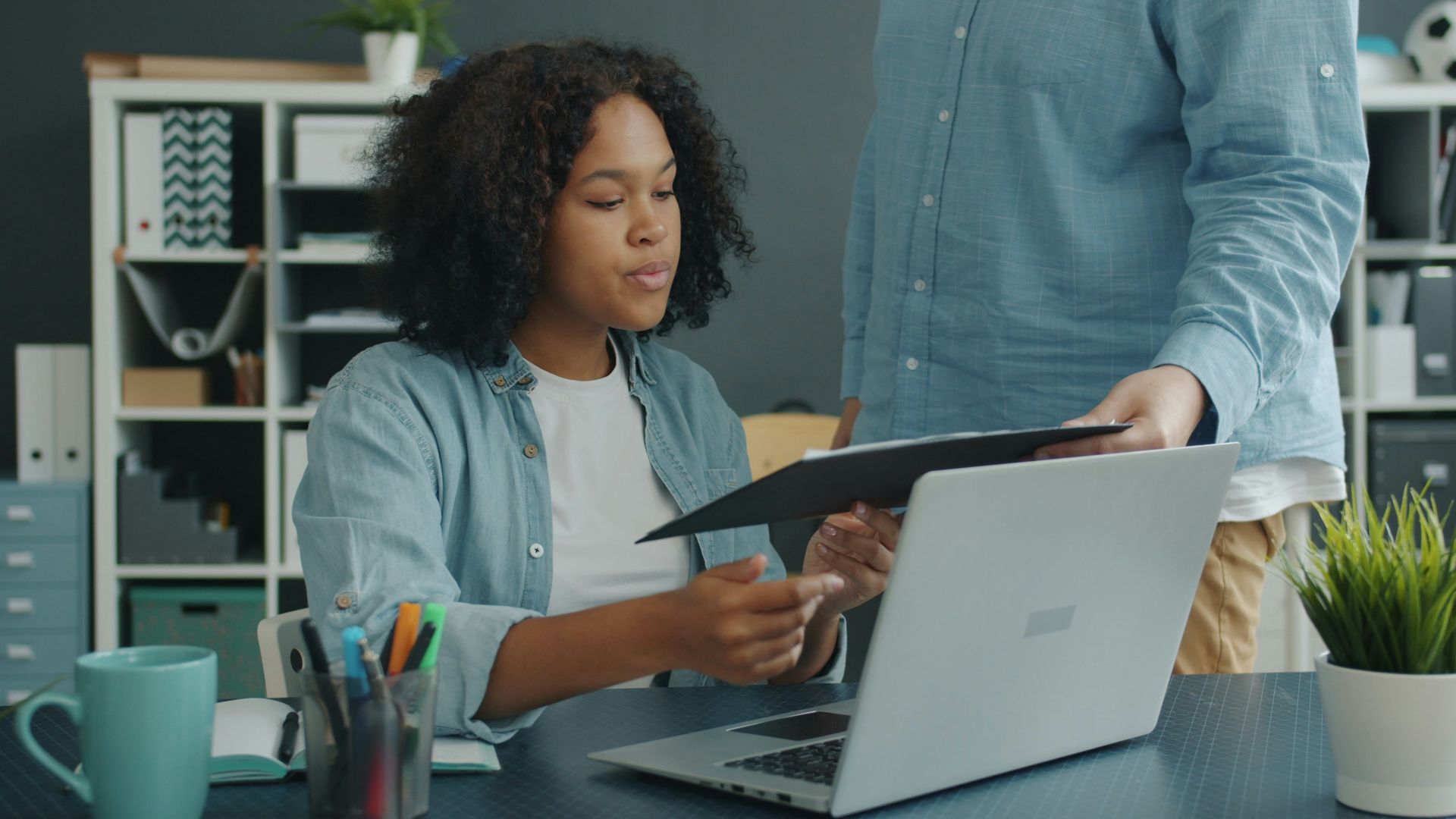 Two colleagues reviewing documents at an office desk.