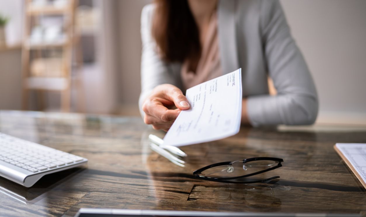 Close-up Of A Businessperson's Hand Holding Cheque In Office