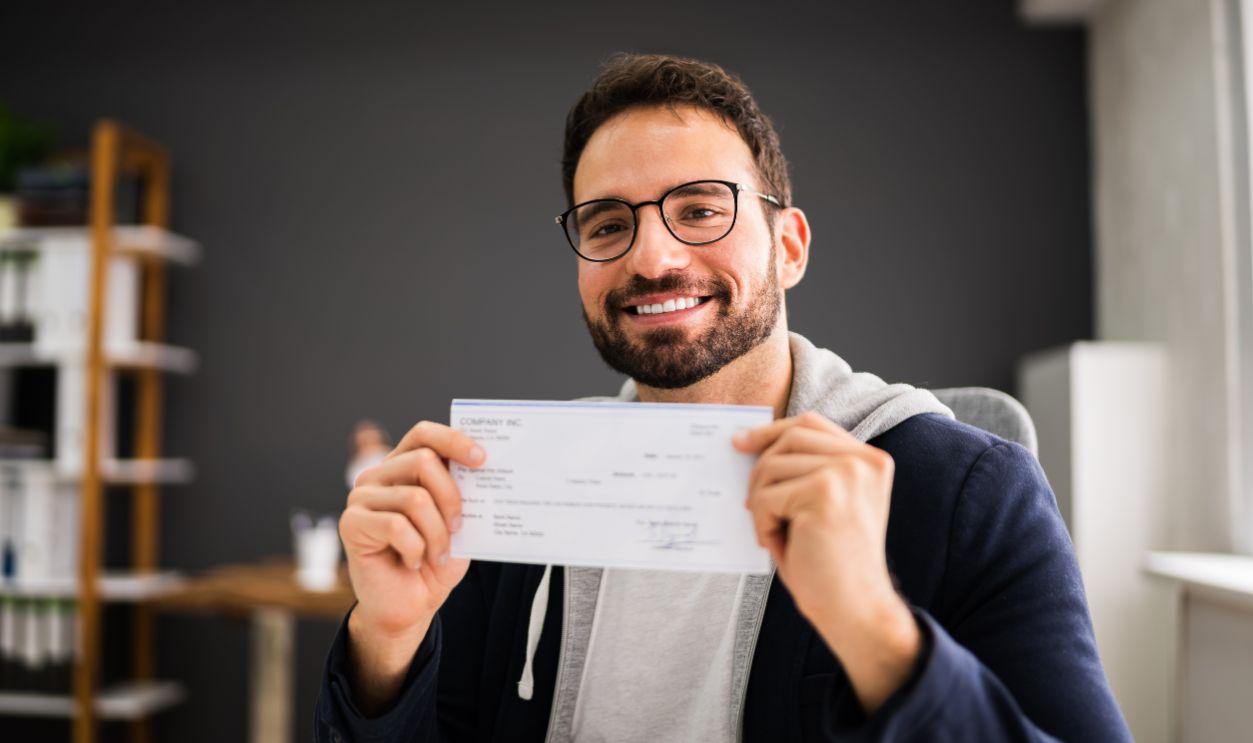 Holding Paycheck Or Payroll Check Or Insurance Cheque In Hand