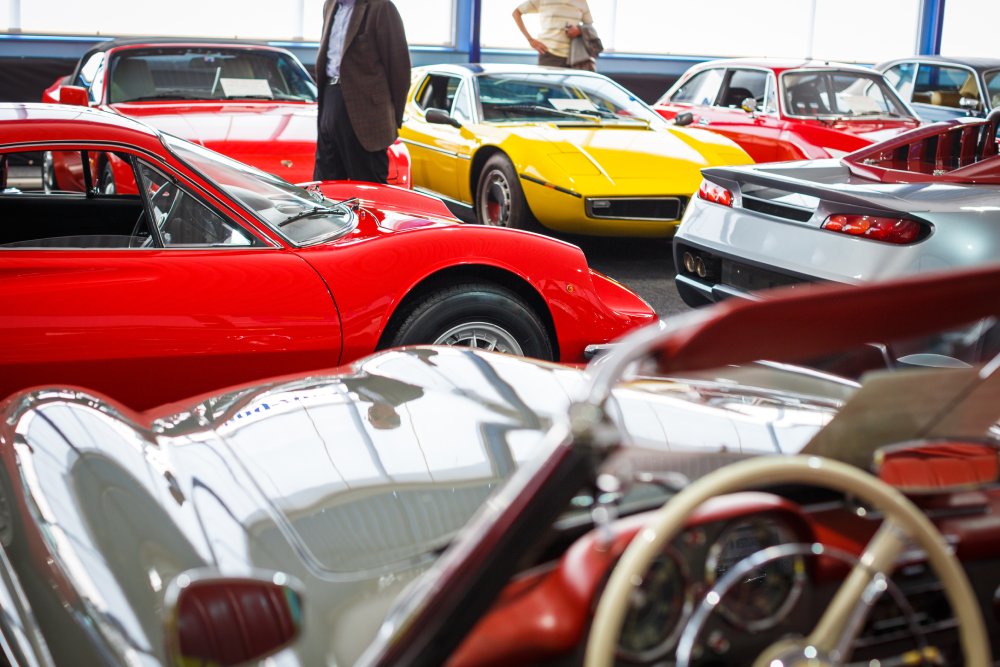 People viewing cars on sale during an expensive old cars auction