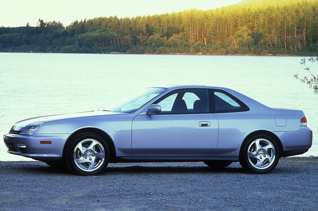 A close-up photo of a Honda Prelude car parked in front of a lake