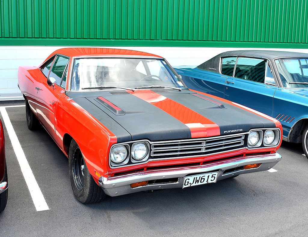 A close-up photo of a 1969 Plymouth Road Runner car parked in a parking lot