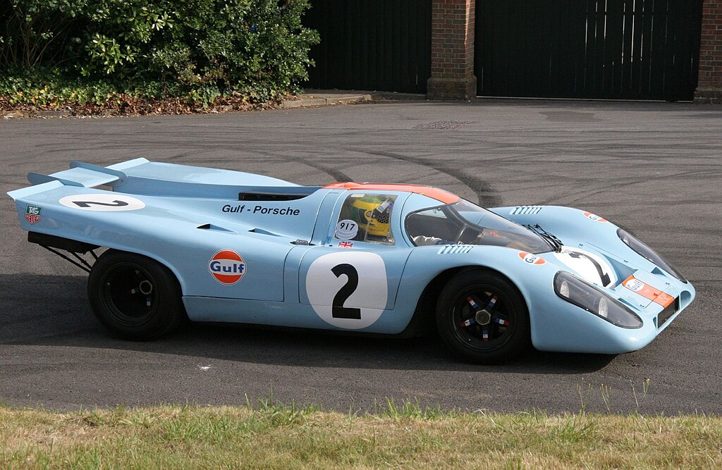 A close-up photo of a Porsche 917K car parked in a parking lot