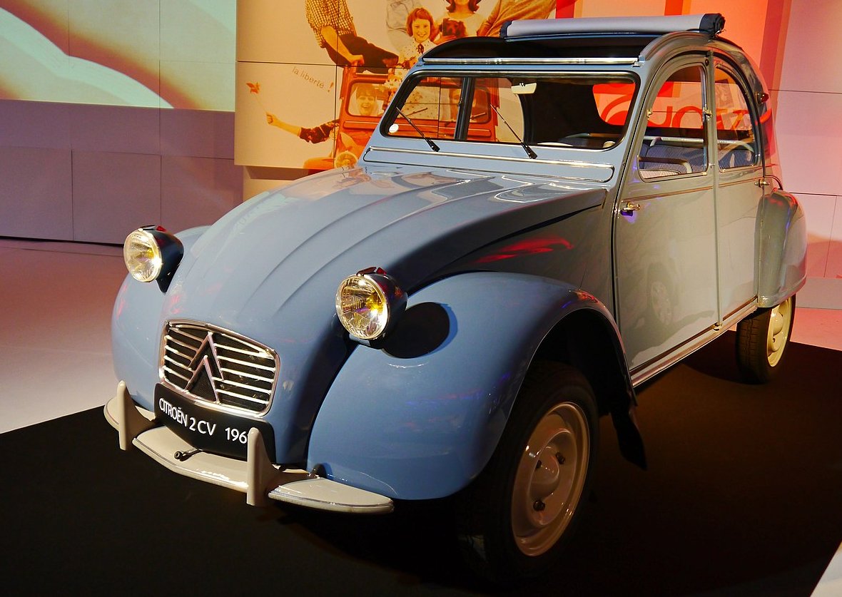A close-up photo of a Citroën 2CV car on display at an exhibition