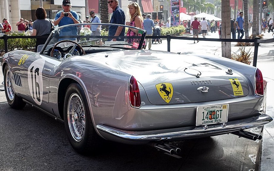 A close-up photo of a Ferrari 250 GT LWB Spyder California car parked on a city street