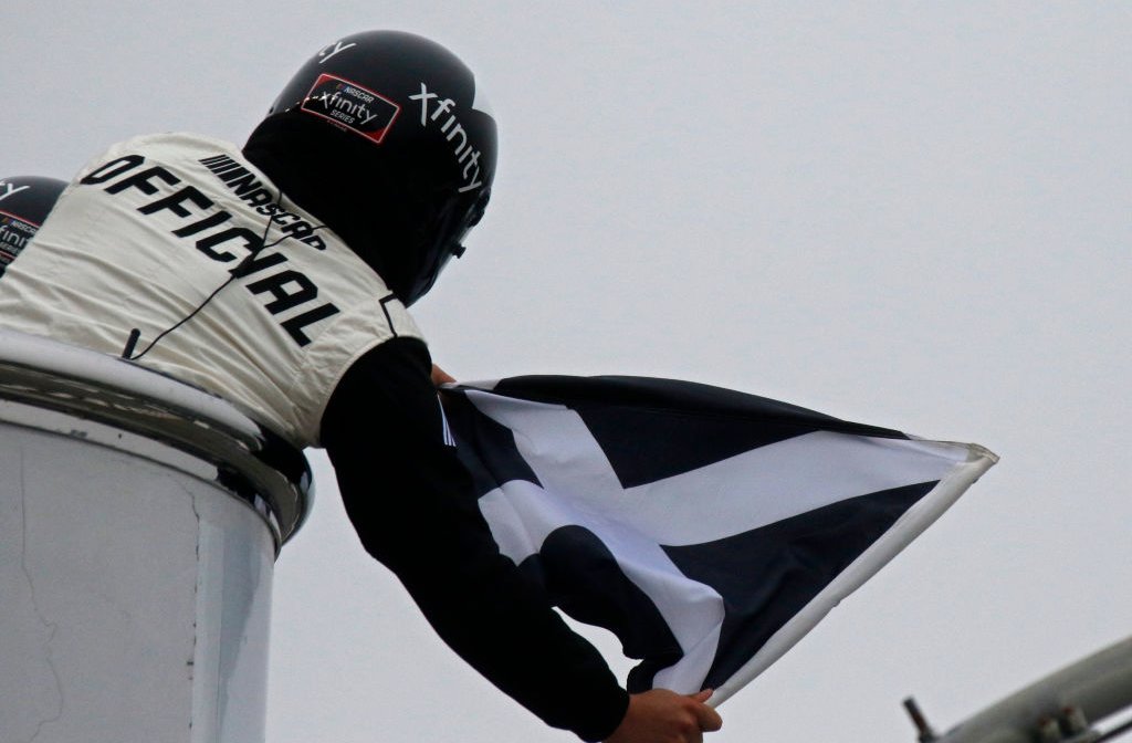 The Xfinity official waves the black flag with a white X to a competitor