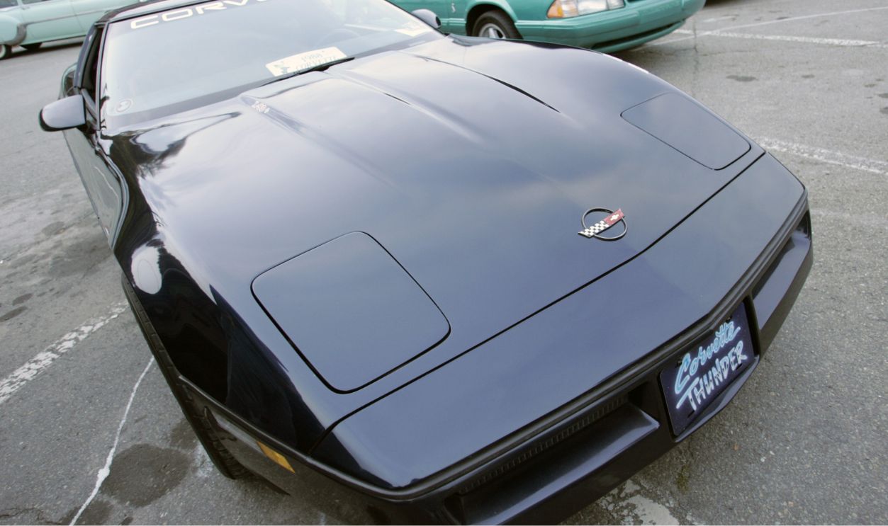 Antique cars line a parking lot for a