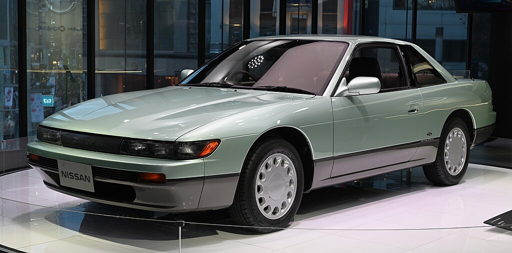 A close-up photo of a Nissan Silvia S13 car on display at an exhibition