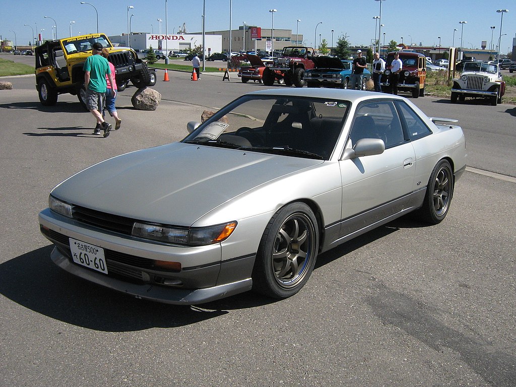 A close-up photo of a Nissan Silvia S13 car on display at an exhibition