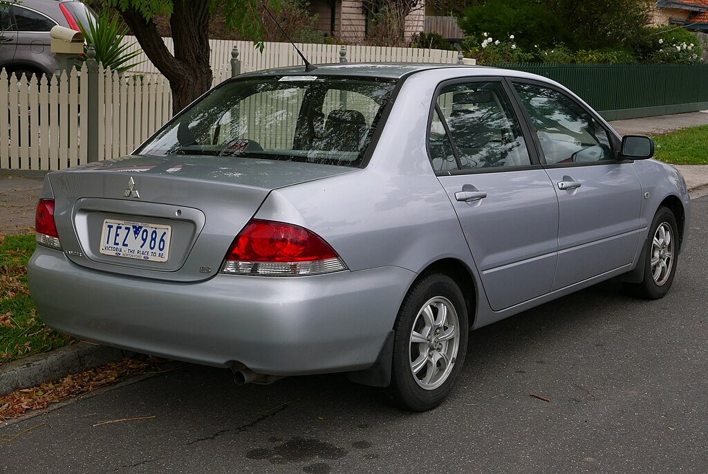A close-up photo of a Mitsubishi Lancer car parked in a parking lot