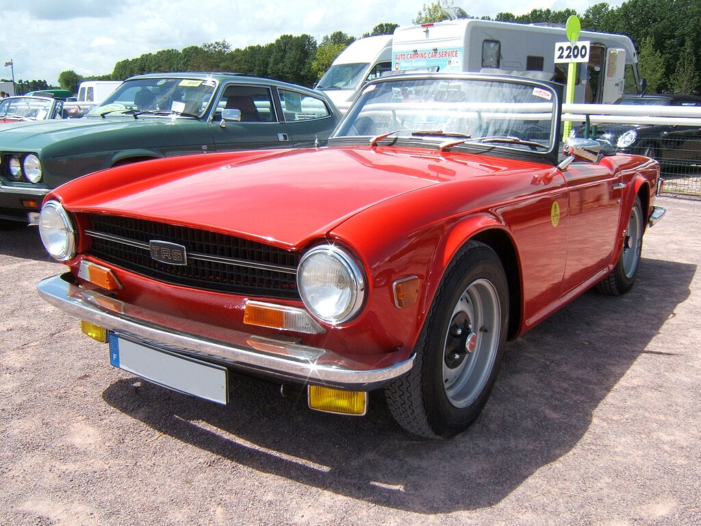 A close-up photo of a Triumph TR6 car parked in a parking lot
