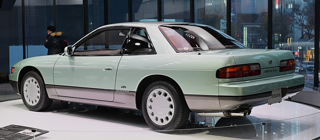 A close-up photo of a Nissan Silvia S13 car on display at an exhibition