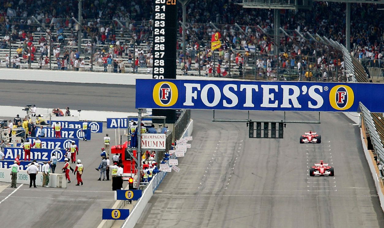 Drivers with Michelin tyres are seen driving in to the pits (R) after the warm-up lap, both Ferrari cars of Michael Schumacher and Rubens Barrichello who are driving on Bridgstone tyres prepare to race on the starting grid during the US F1 Grand Prix on June 19, 2005 in Indianapolis, Indiana.