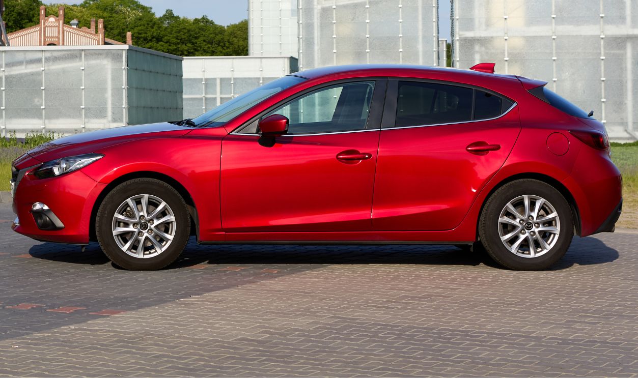 Red Mazda 3 with the buildings of the Silesian Museum in the background. Katowice, Poland 22.05.2016