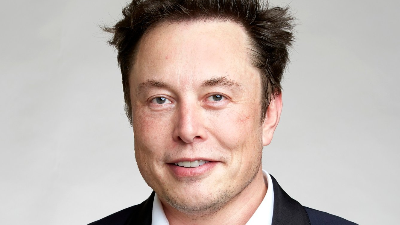 Portrait Photo of Elon Musk in dark suit, facing the camera.