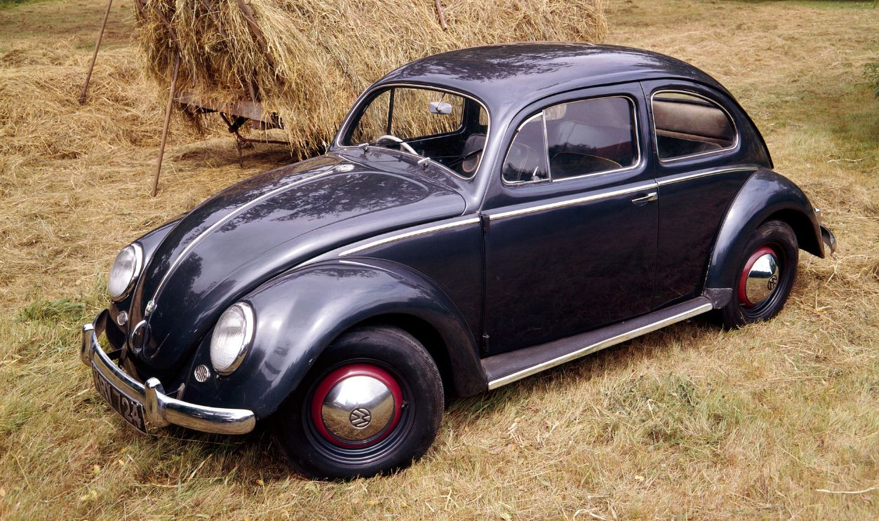 A 1953 Volkswagen Export Type I Beetle. This example was presented to Lord Montagu of the National Motor Museum at Beaulieu in 1963, to commemorate the sale of the first 100,000 cars in Britain. Ferdinand Porsche produced ancestral KdF-wagen prototypes in 1935. Batches of pre-production versions followed, before manufacture began in 1939, adapted for military use. Adolf Hitler advised that the Volkswagen People's Car be streamlined to 'look like a beetle'. Post-war civilian production was under British military control until 1949, when it reverted to German charge. During the late 1960s the Beetle became a world car. In 1981 the 20 millionth unit was built, smashing the Ford Model T's record of around 15 million. 