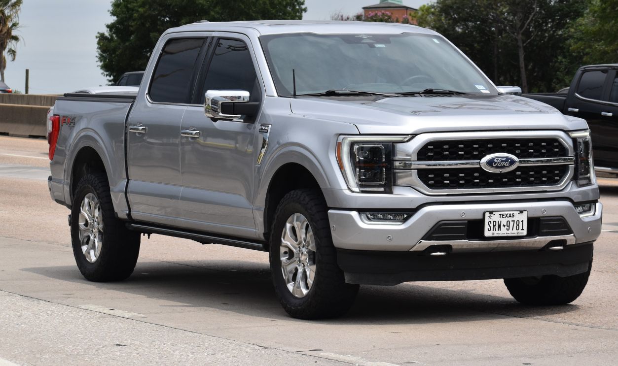 A portrait of a gray Ford F-150 pick-up truck traveling down a highway in moderate traffic