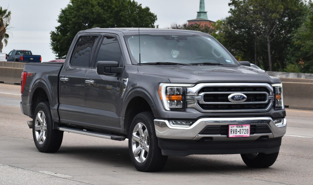  A portrait of a gray Ford F-150 pick-up truck traveling down a highway in moderate traffic