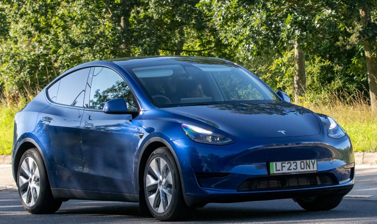  Blue 2023 Tesla Model Y RWD electric car driving on an English country road.