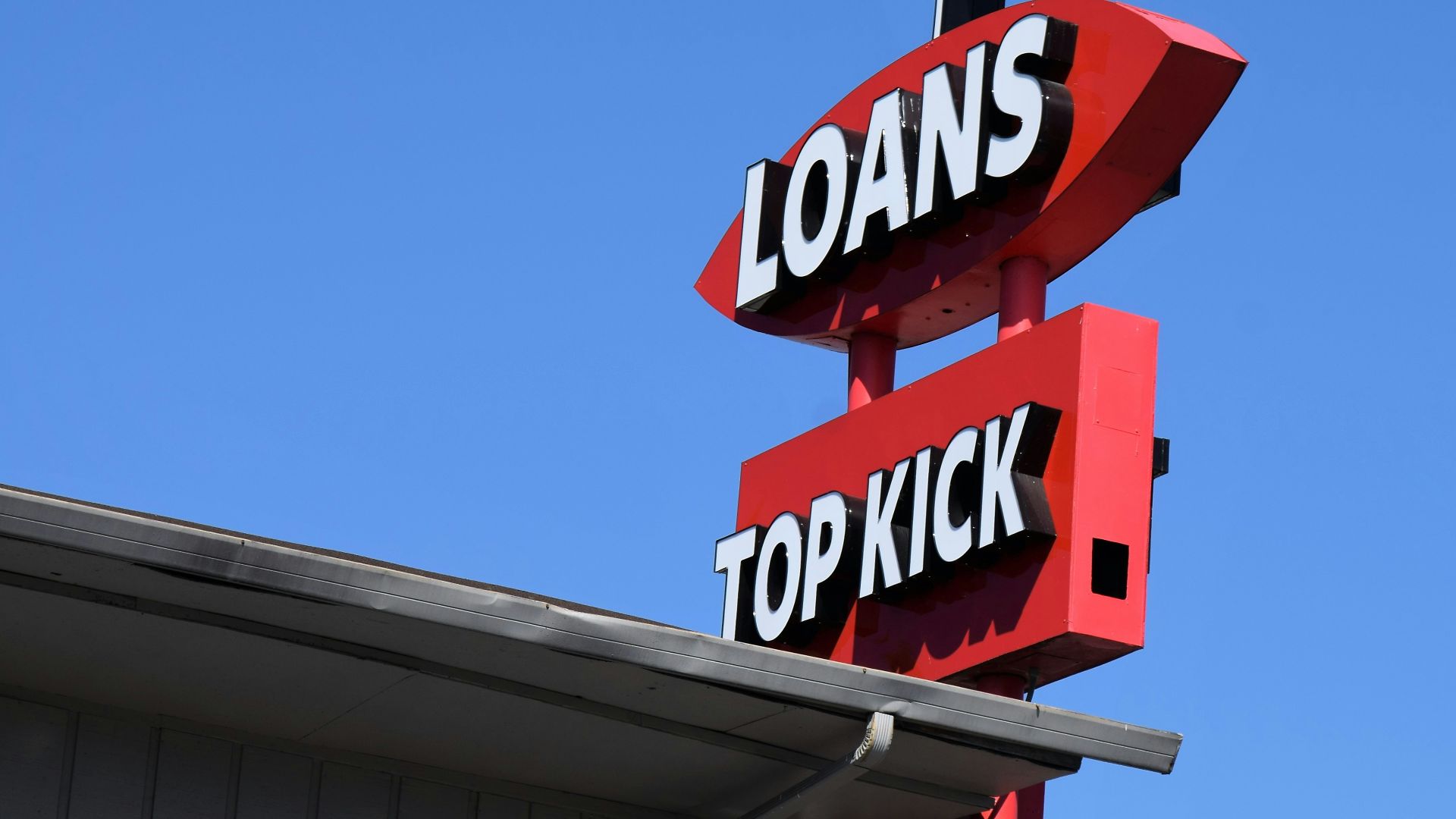 a sign for a top kick store against a blue sky