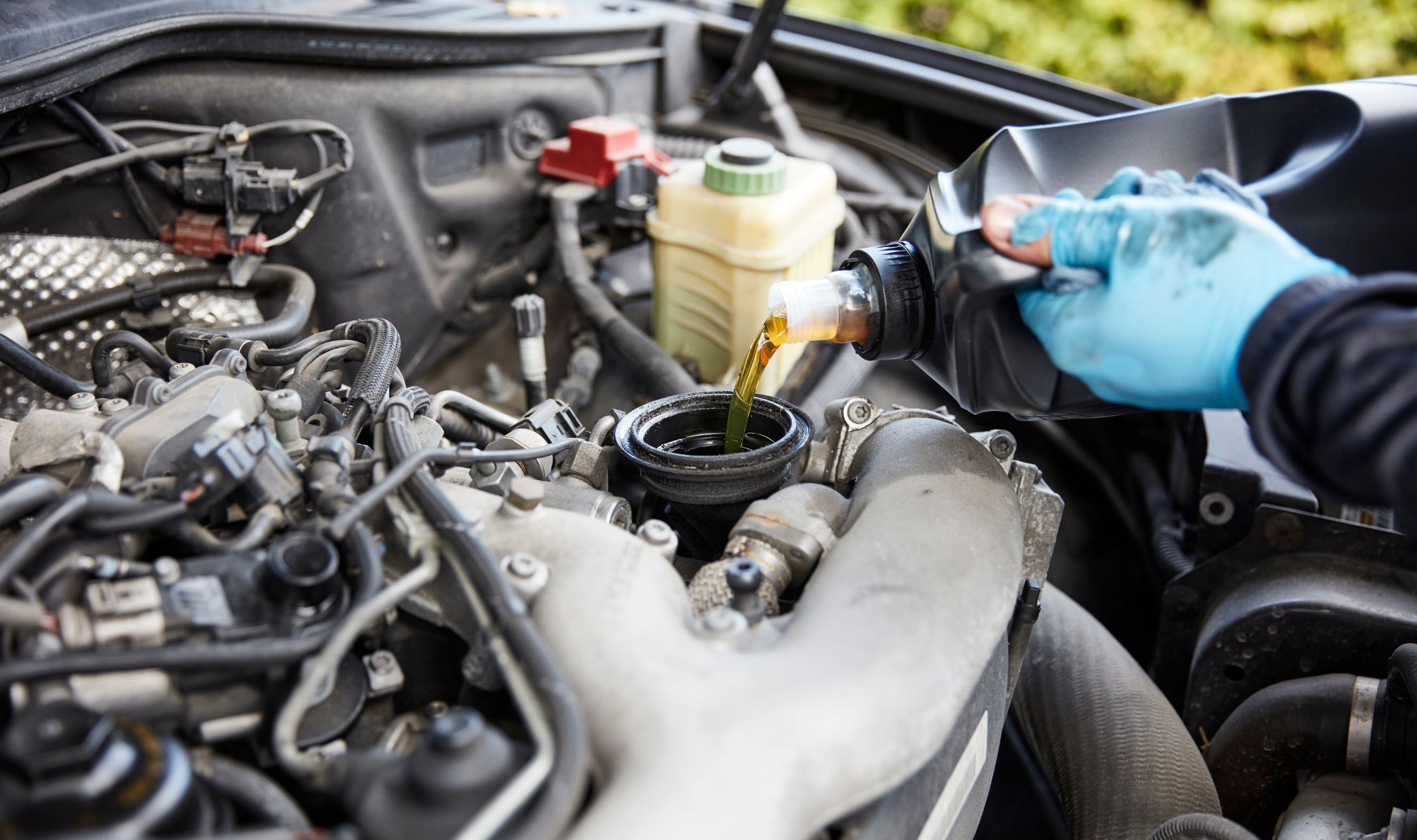 Pouring motor oil for motor vehicles from a gray bottle into the engine. Oile Change