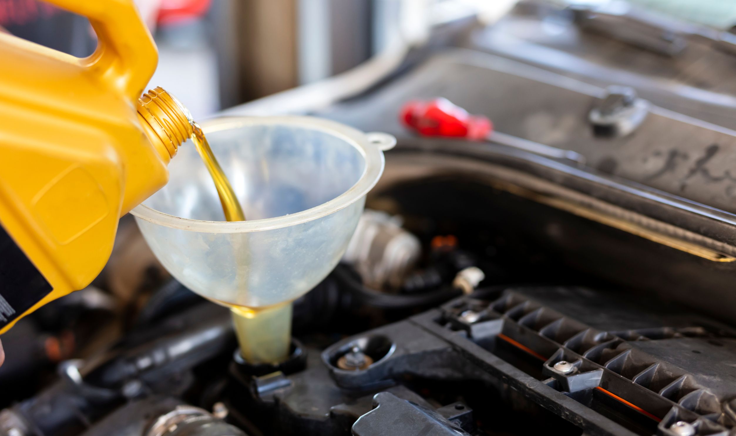 Pouring motor oil for motor vehicles from a gray bottle into the engine