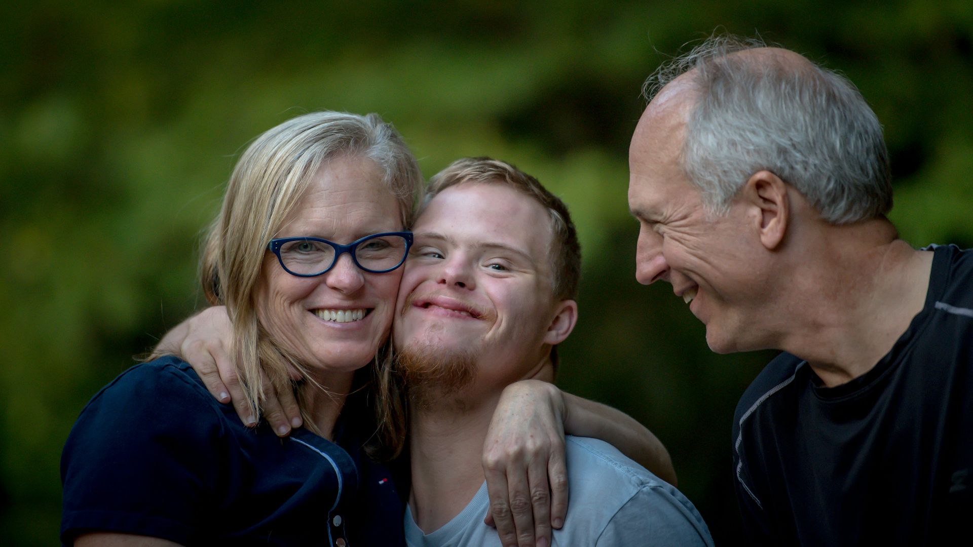photo of two man and one woman standing near tree