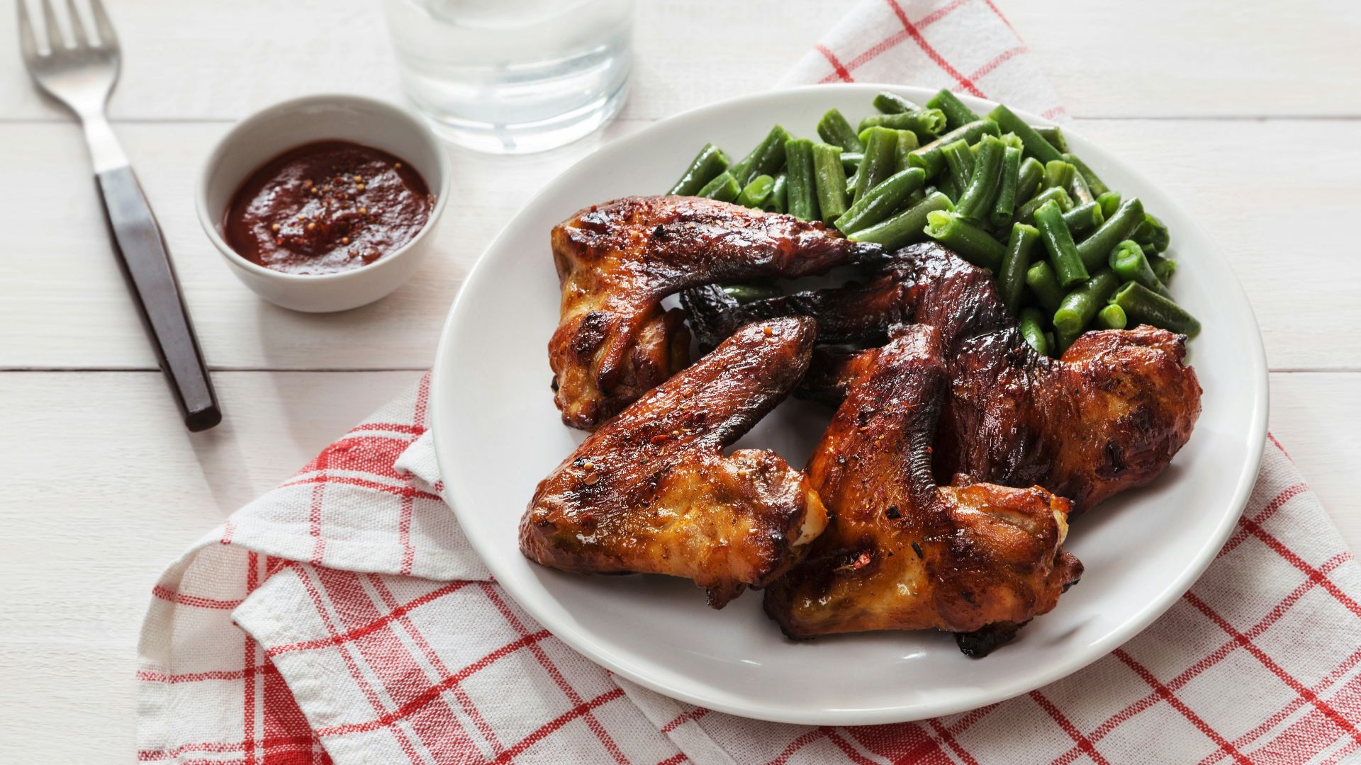 A white plate topped with meat and green beans