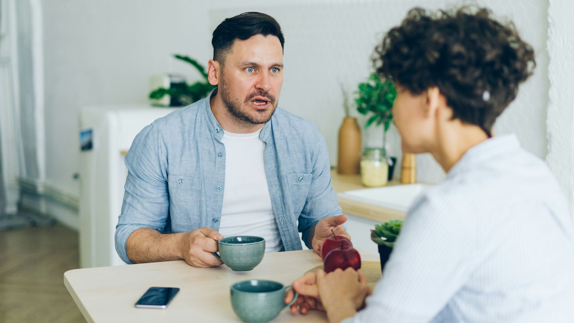 a man sitting at a table talking to a woman
