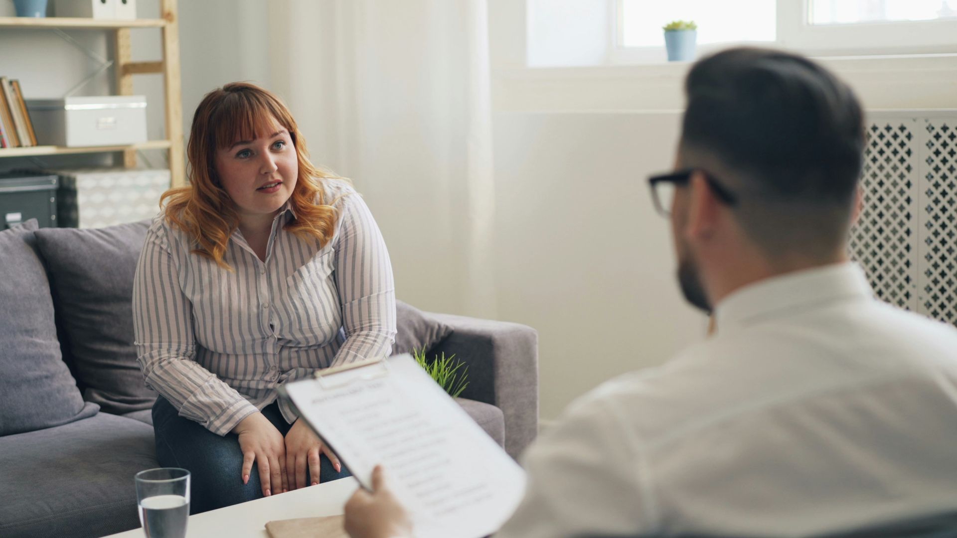 a woman sitting on a couch talking to a man
