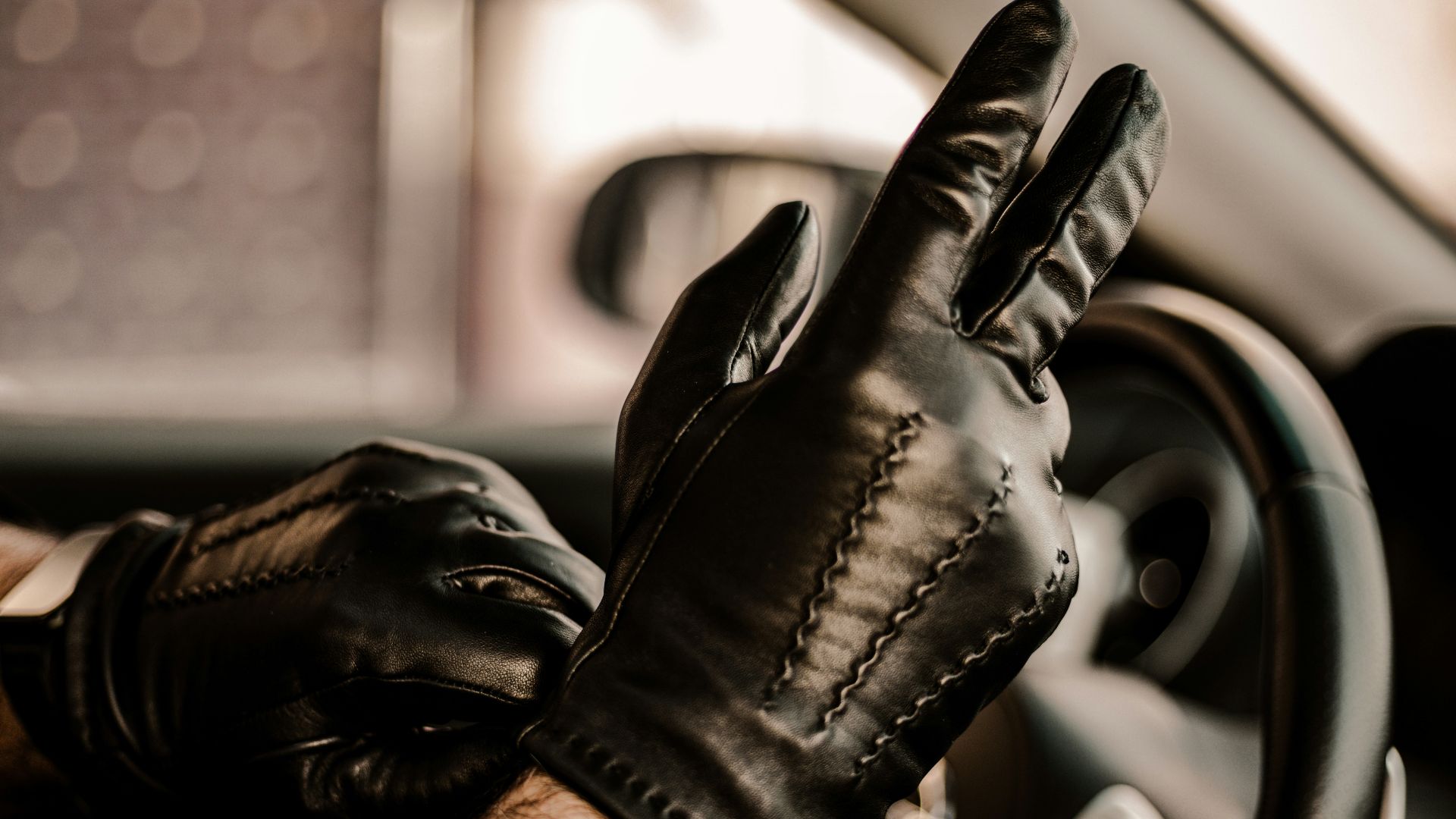 a man wearing black leather gloves driving a car