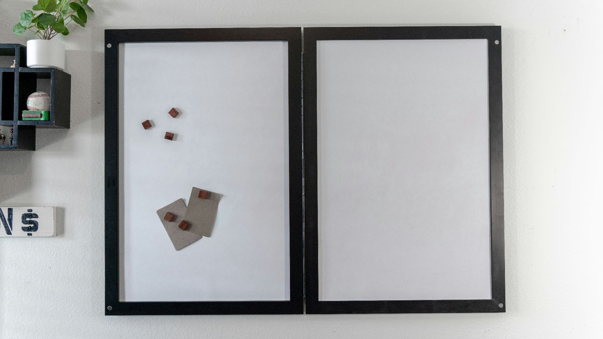 a white wall with a black frame and a picture of a piece of paper on