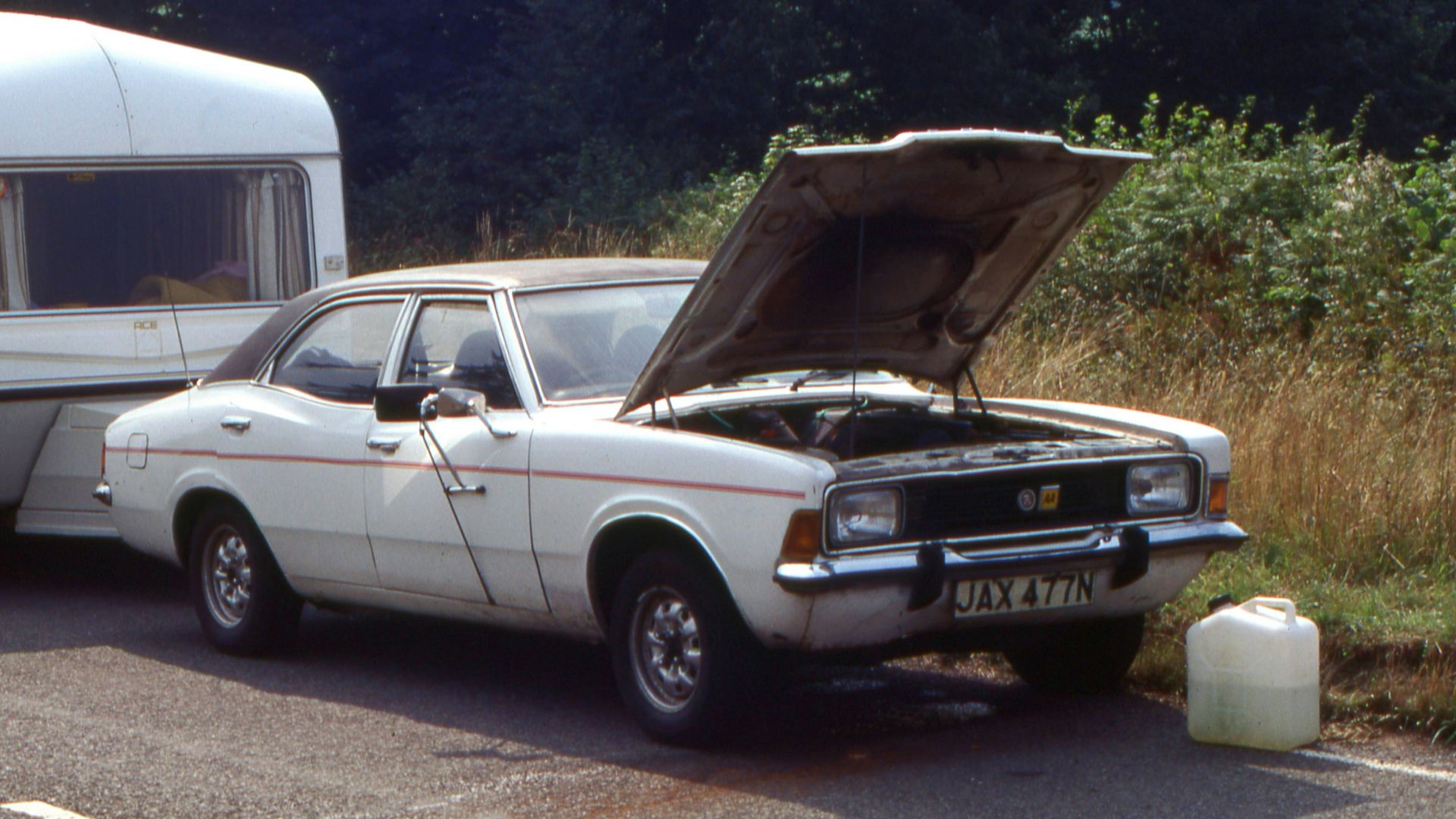 a car with a camper on the back of it parked next to a truck