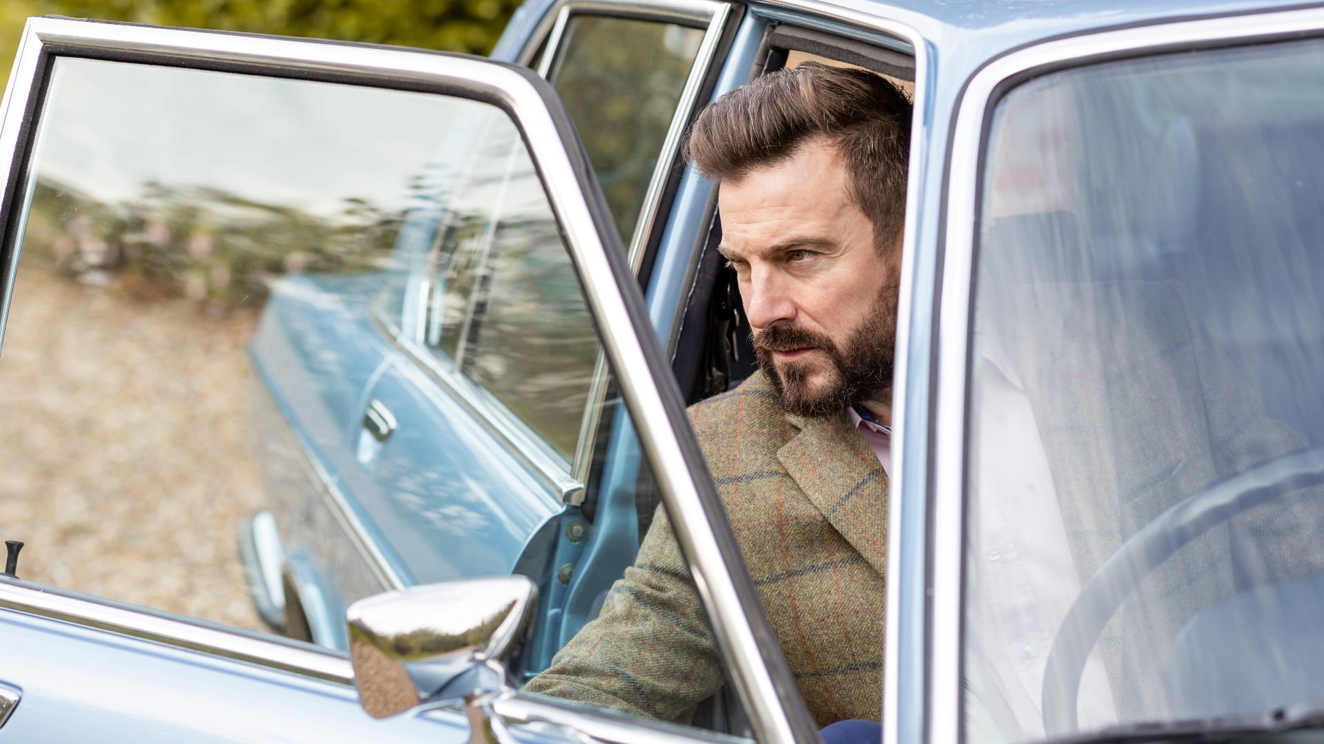 a man sitting in a car looking out the window