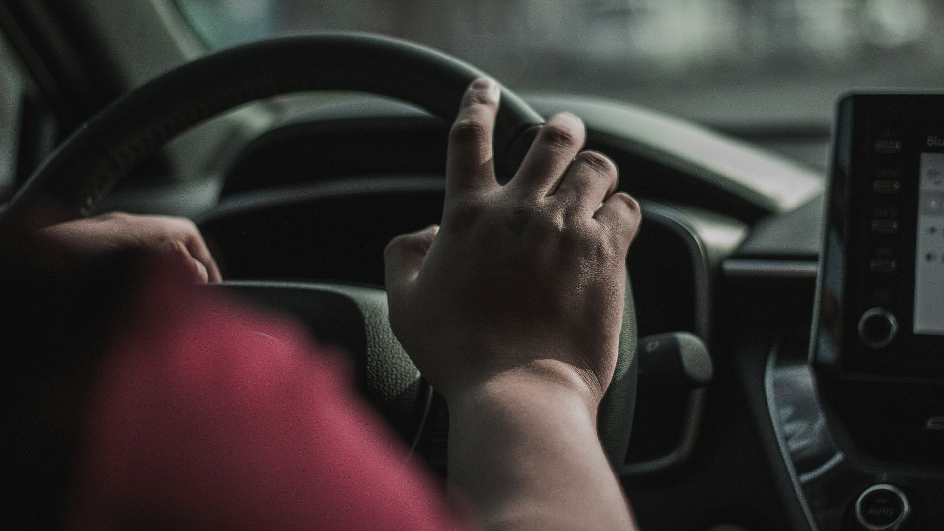 a person driving a car with their hand on the steering wheel