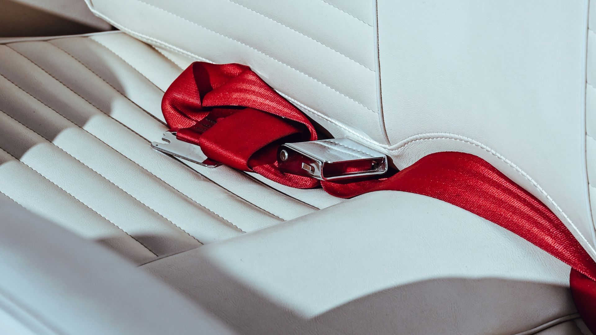 White car seat with red seatbelt.