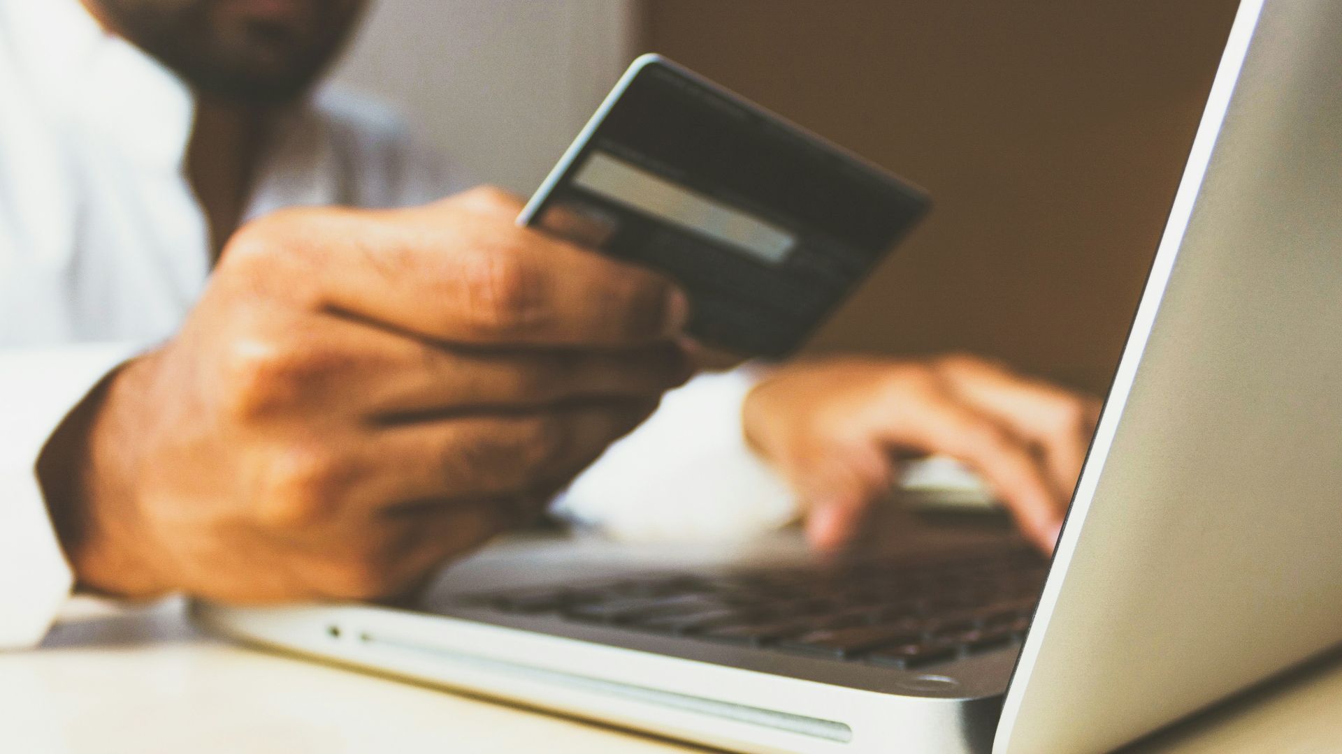 person using laptop computer holding card