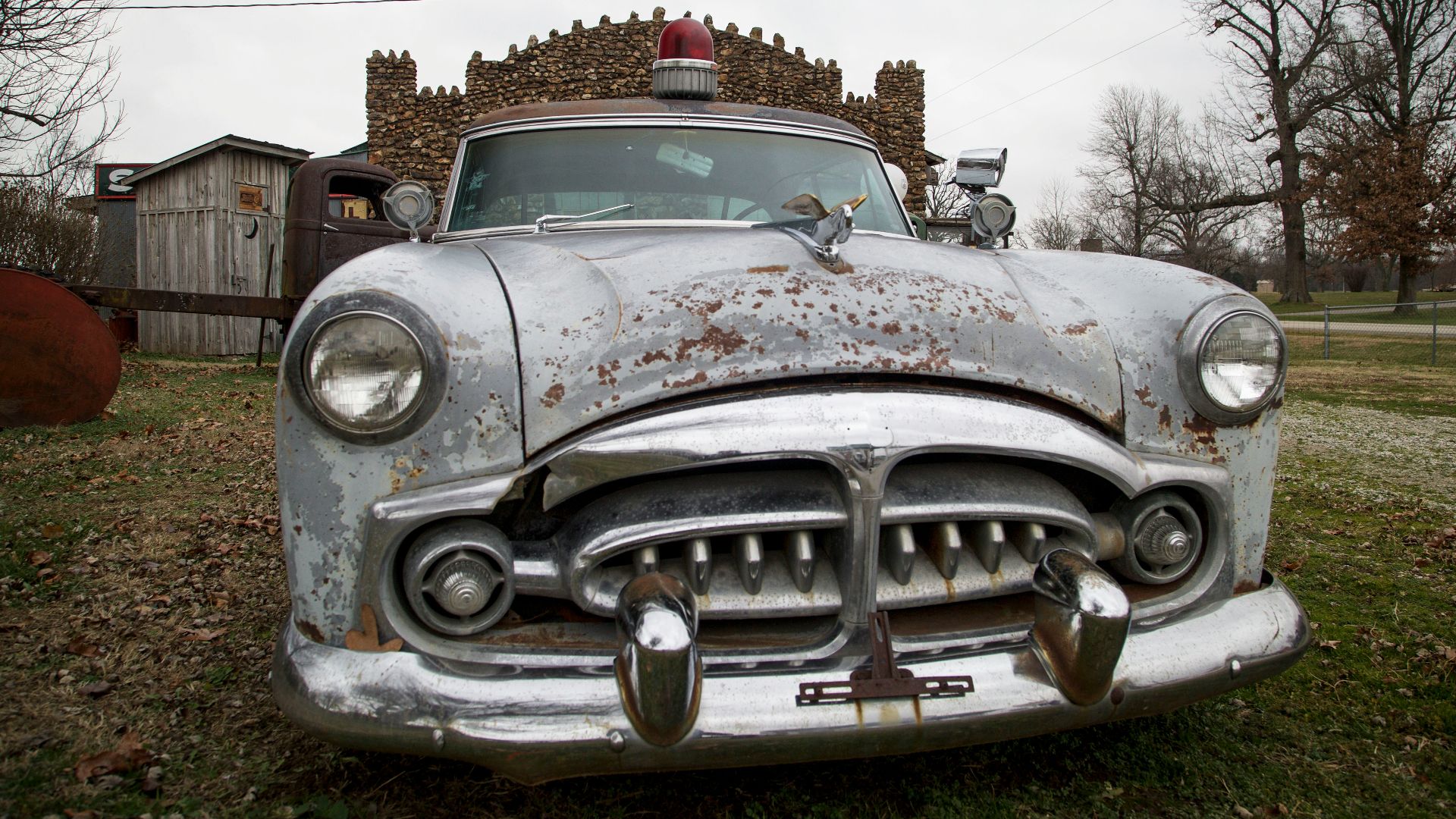 an old car parked in a field with a house in the background