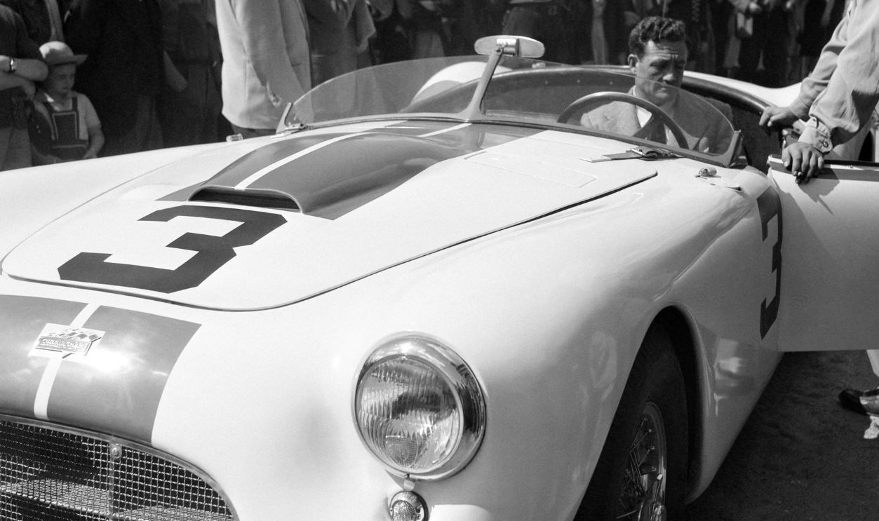 US driver Briggs Cunningham sits in his Cunningham C-2R car n°3 while his teammate US driver George Huntoon (R) looks on, on June 16, 1951 in the centre of Le Mans, during the administrative and technical checks of racing cars for the 19th edition of the 24 hours of Le Mans, commonly known in English as