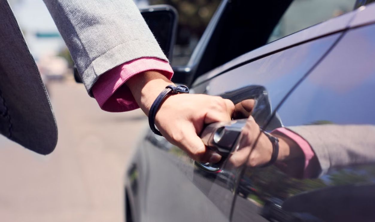 Close-up image of a hand opening a car door, highlighting business and transit themes