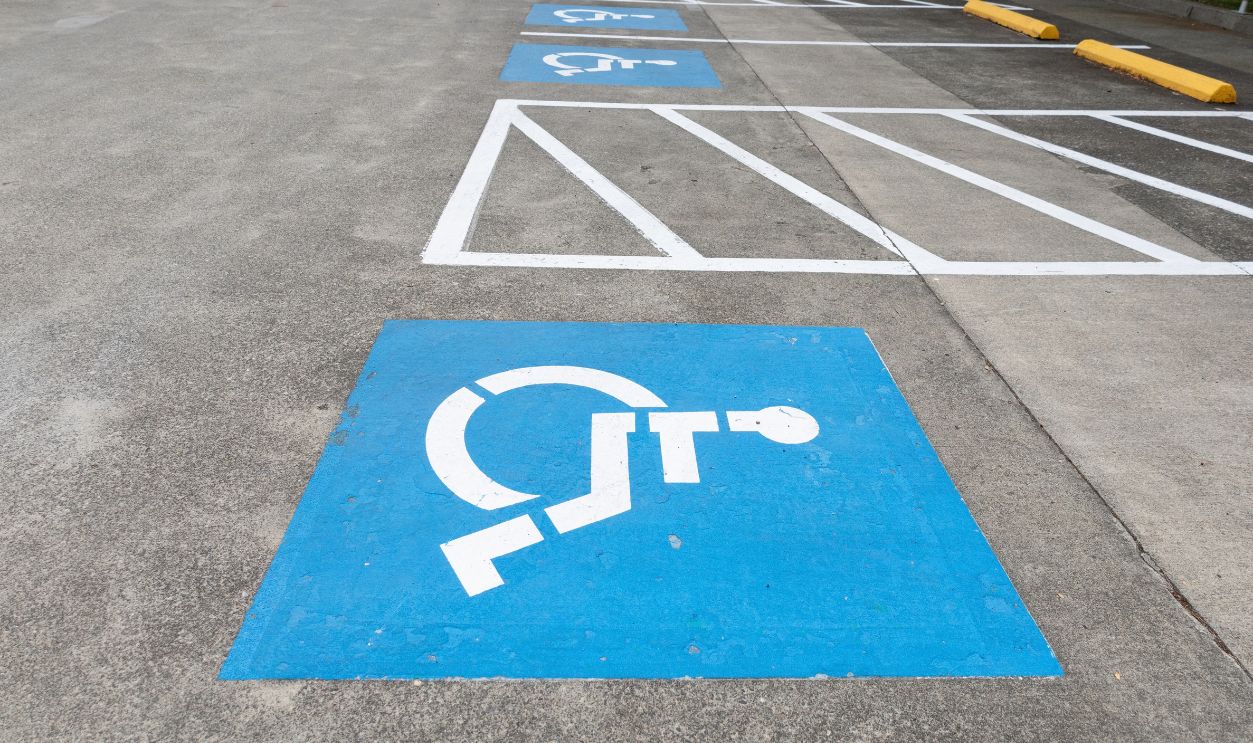 Multiple accessible parking spaces marked with blue wheelchair symbols and striped access aisles in an empty parking area.