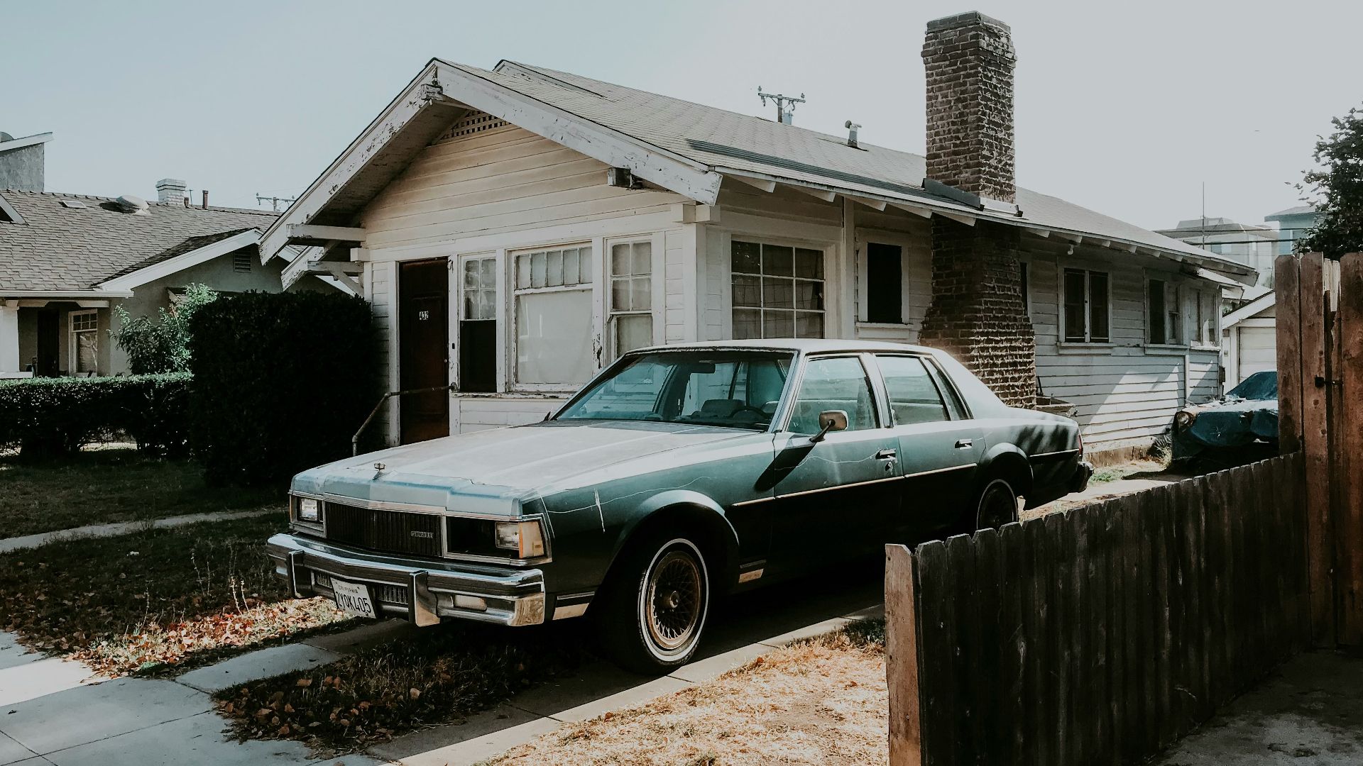 black sedan parked beside brown wooden fence