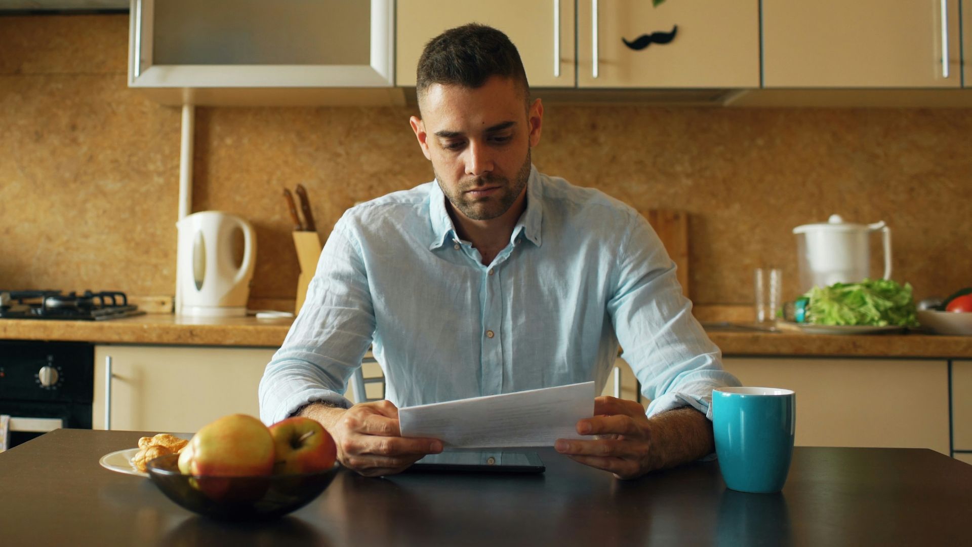 Man reading document at kitchen table with coffee