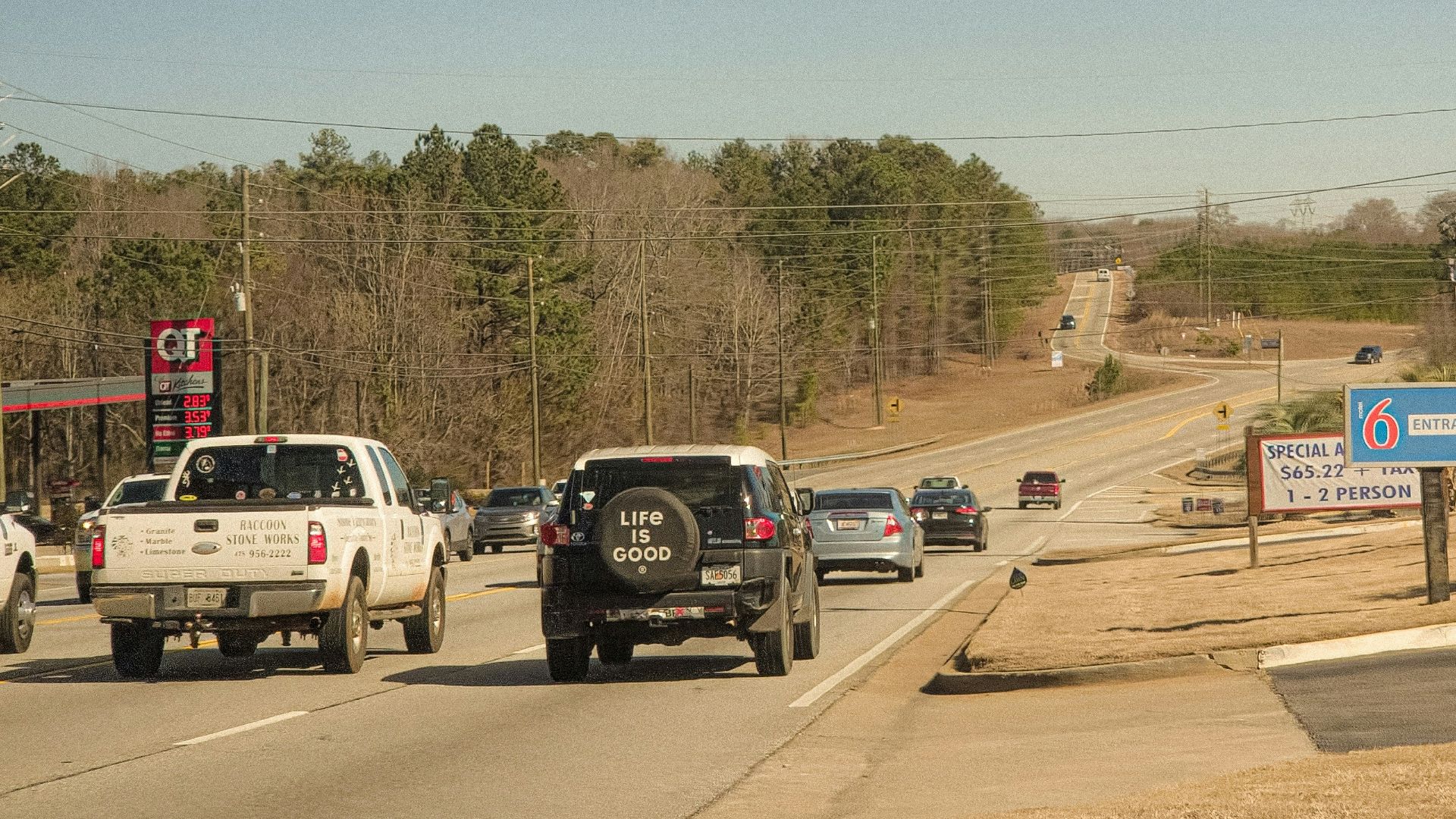 Cars driving on a highway with roadside businesses