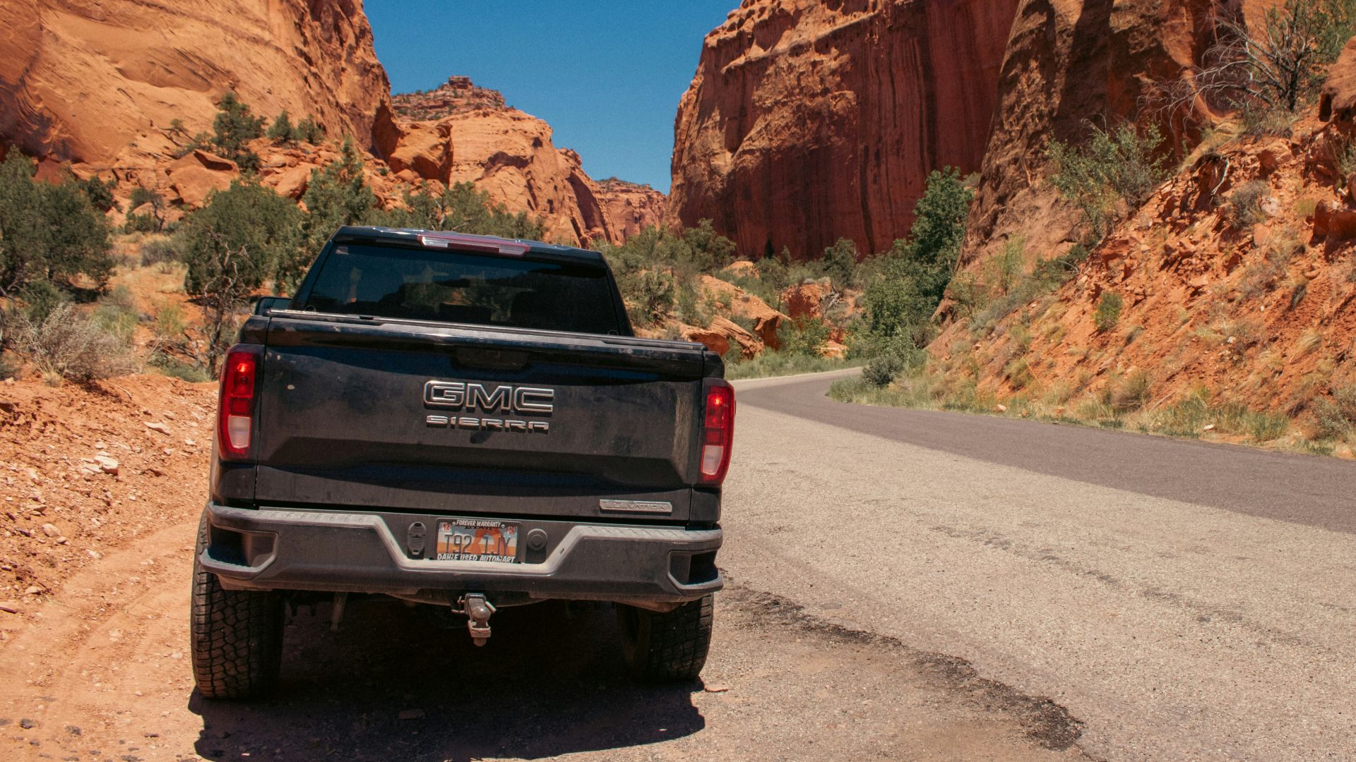 A black truck driving down a desert road